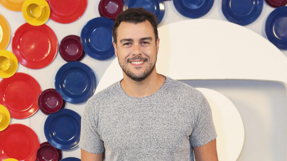 Joaquim Lopes na frente de painel com logo da Globo