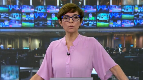 Renata Lo Prete durante apresentação do Jornal da Globo. Ela está usando um figurino da cor rosa no cenário provisório dos telejornais de São Paulo