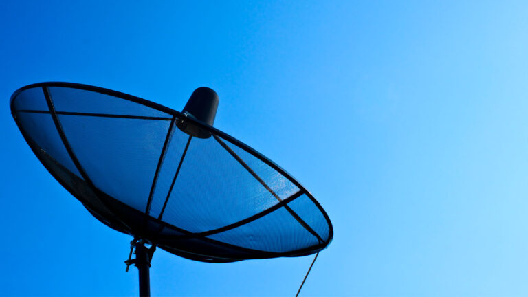 Antena parabólica apontada para o satélite com céu azul, sem nuvens, ao fundo