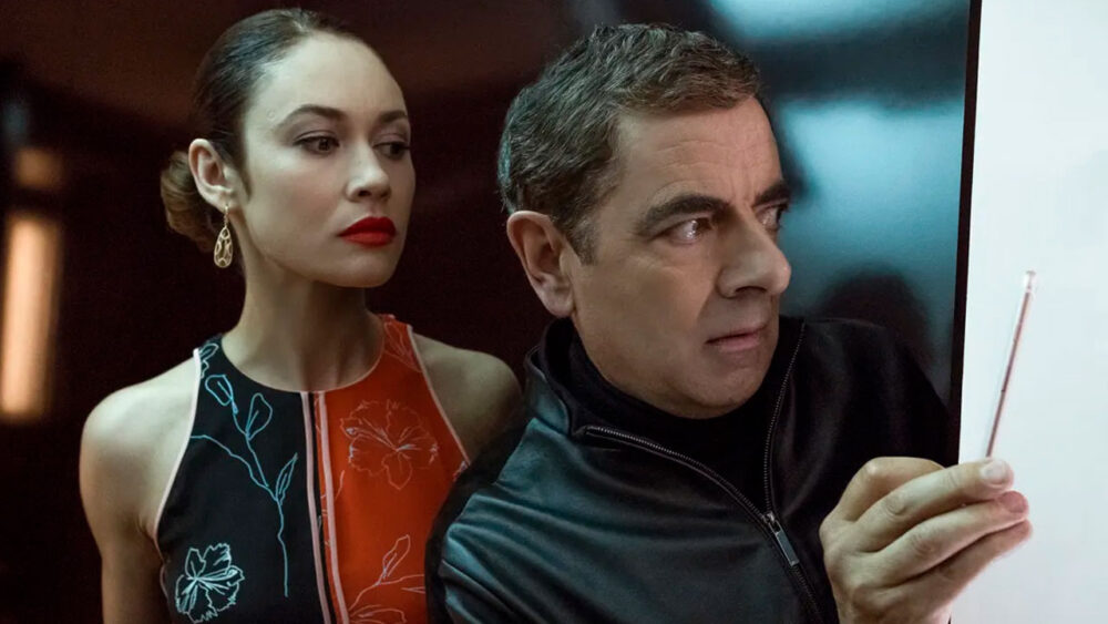 Olga Kurylenko e Rowan Atkinson no filme Johnny English 3.0, que será exibido pela Record