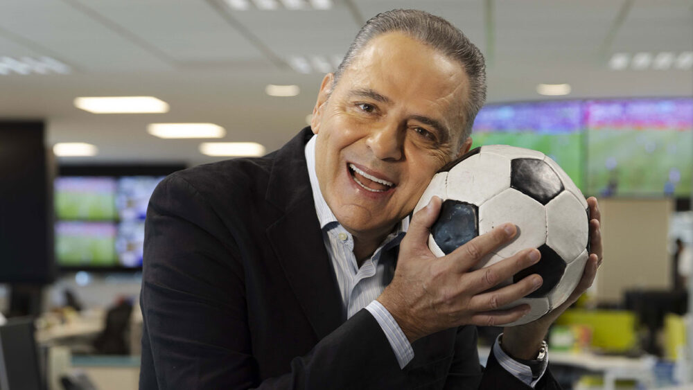 Narrador da Globo, Luis Roberto aparece segurando uma bola de futebol perto do rosto