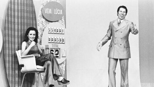 Imagem com foto preto e branco de Silvio Santos ao lado de participante no programa dele na Globo