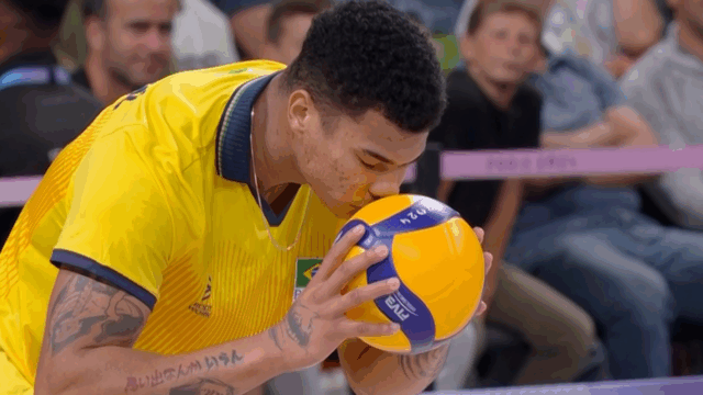 Darlan, jogador da seleção masculina de vôlei beija bola durante partida contra a Itália, exibida pela Globo