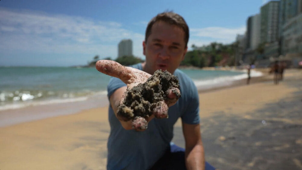 Mário Bonella segurando areia do litoral do Espírito Santo, que será tema do Globo Repórter