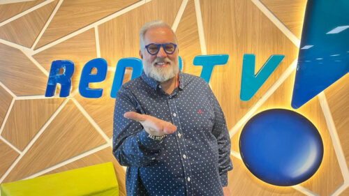 Leão Lobo em foto em frente ao logo da RedeTV!