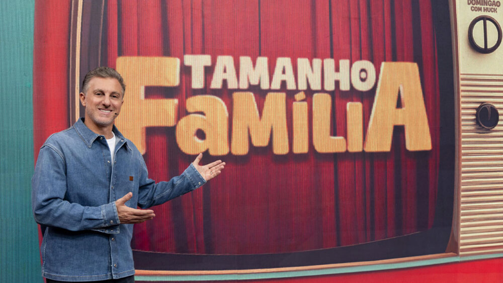 Luciano Huck em frente ao telão com o logo do Tamanho Família no Domingão