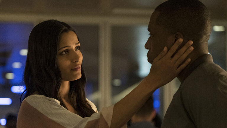 Freida Pinto, com blusa de listras, toca o rosto de Leslie Odom Jr. em cena do filme de ficção científica Agulha no Palheiro Temporal