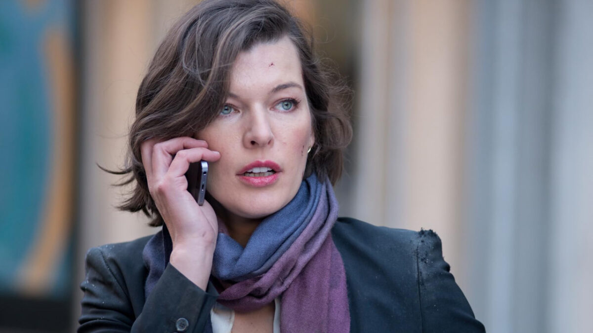 Milla Jovovich com expressão tensa ao celular em cena do filme Perseguindo Abbott (2015) exibido pela Record