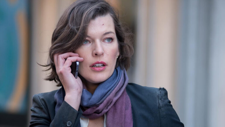 Milla Jovovich com expressão tensa ao celular em cena do filme Perseguindo Abbott (2015) exibido pela Record