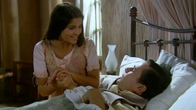 Zuca (Vanessa Giácomo) segura a mão de Luís Jerônimo (Daniel de Oliveira), que está deitado na cama doente, em cena de Cabocla