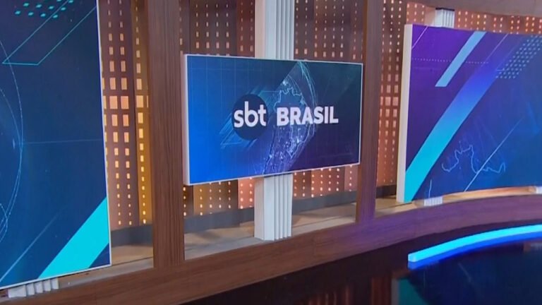 Imagem com foto do monitor com logo do SBT Brasil no estúdio do jornal