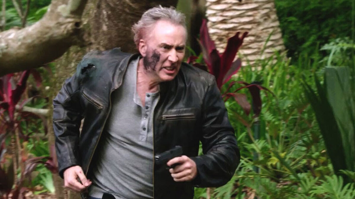 Nicolas Cage com o rosto sujo e arma na mão correndo em cena do filme Vingança ao Anoitecer