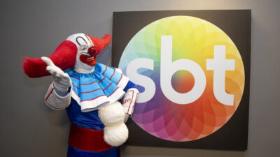 O palhaço Bozo ao lado de um painel com o logo do SBT
