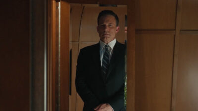 Ben Affleck usando terno e se olhando no espelho em cena do filme O Contador 2