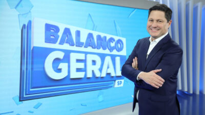 Eleandro Passaia sorrindo com os braços cruzados no estúdio do Balanço Geral SP