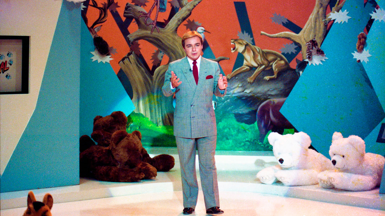 Gugu Liberato apresenta o programa TV Animal em um cenário temático com ilustrações de animais e ursos de pelúcia espalhados pelo palco