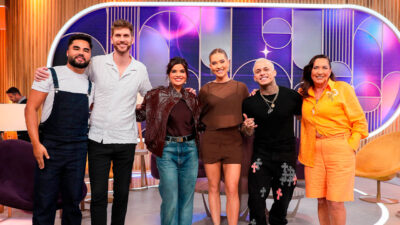 Lucas Guedez, Paul Cabannes, Vanessa Giácomo, Virginia Fonseca, MC Pedrinho e Margareth Serrão posam juntos no palco do Sabadou com Virgínia, do SBT, sorrindo para a câmera