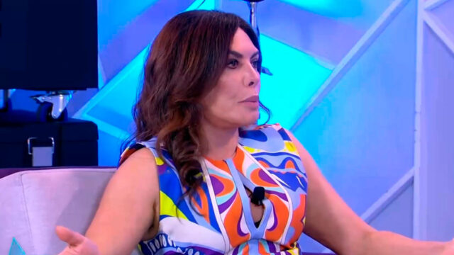 Márcia Goldschmidt no programa Sensacional, gesticulando enquanto fala, com cenário iluminado em tons de azul ao fundo