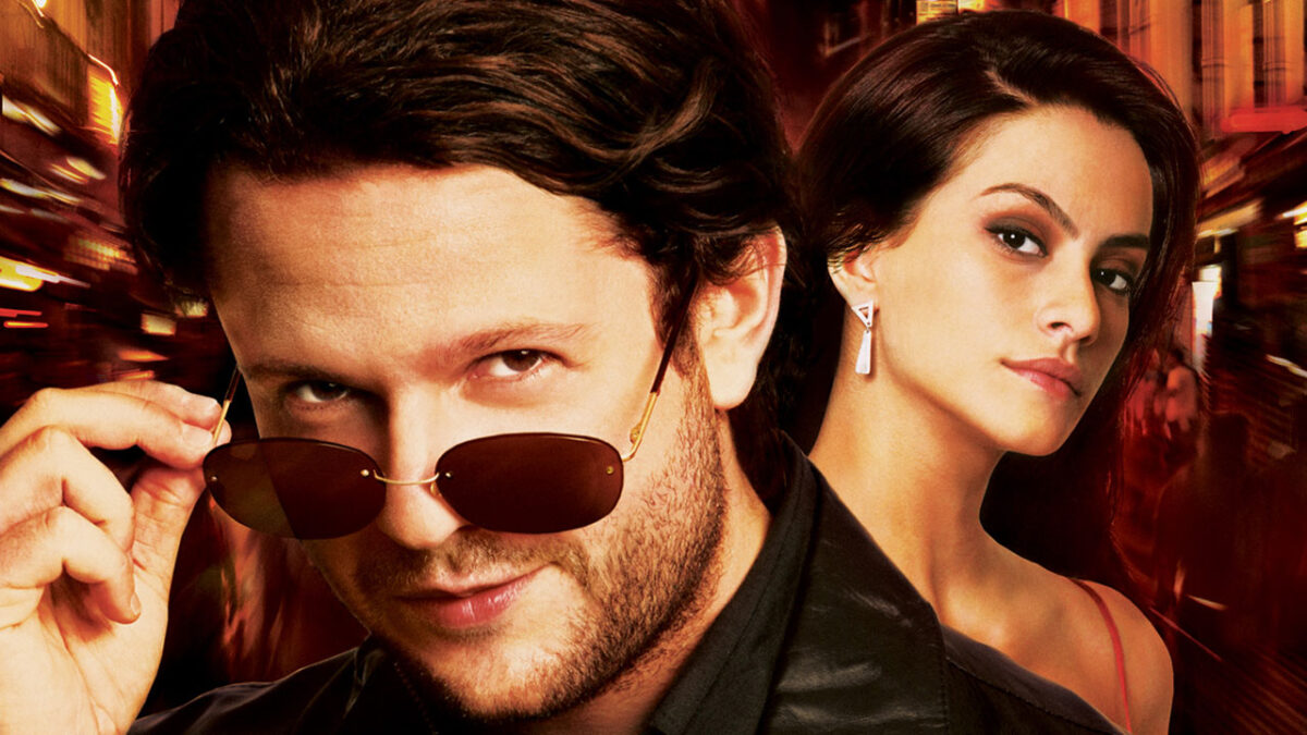 Selton Mello e Cléo Pires no pôster do filme Meu Nome Não é Johnny com fundo desfocado de cidade iluminada à noite