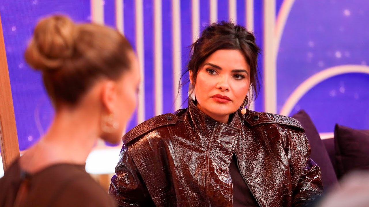 Vanessa Giácomo, usando jaqueta de couro marrom, olha para Virginia Fonseca, que aparece de costas, durante conversa no Sabadou com Virginia