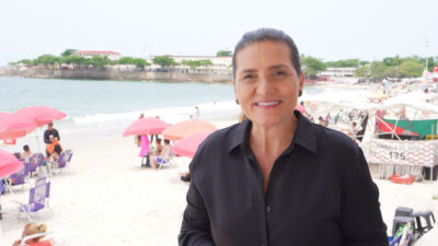 Bette Lucchese grava reportagem do Globo Repórter na praia de Copacabana com barracas e banhistas ao fundo