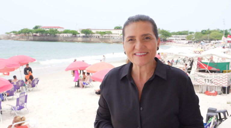 Bette Lucchese grava reportagem do Globo Repórter na praia de Copacabana com barracas e banhistas ao fundo