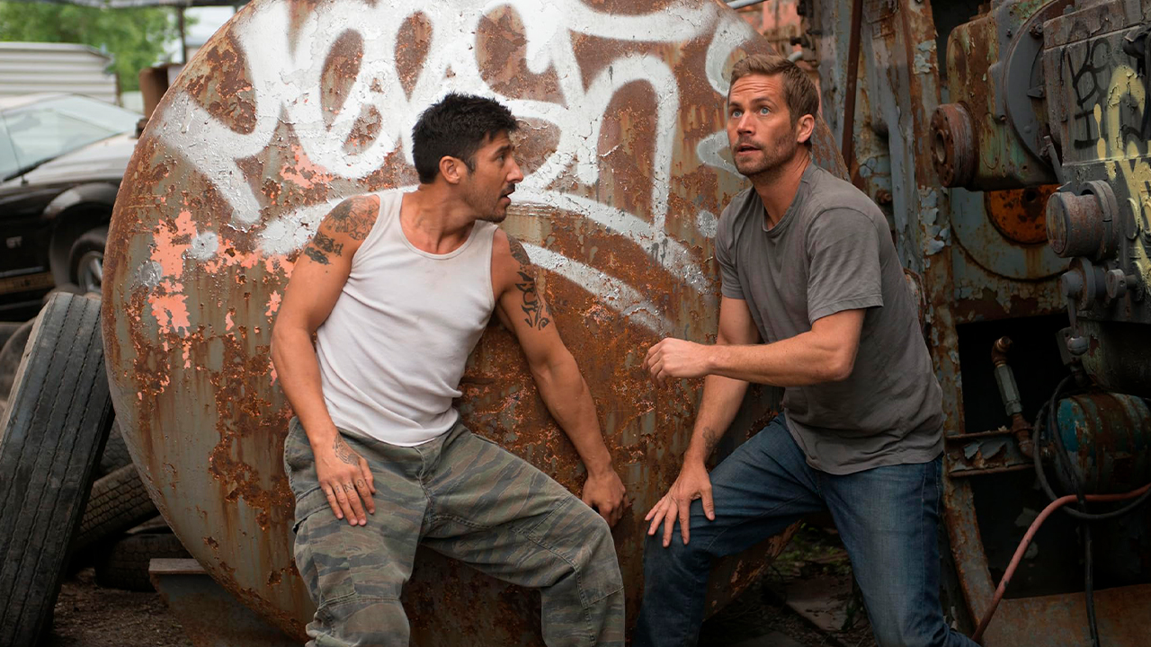David Belle e Paul Walker se escondem atrás de um tanque enferrujado em um ferro-velho no filme 13° Distrito (2014)