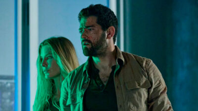Jesse Metcalfe e Kelly Greyson aparecem tensos em um ambiente escuro e iluminado por luz verde, com o rosto do ator sujo de sangue, em cena do filme Fortaleza: O Olhar do Sniper
