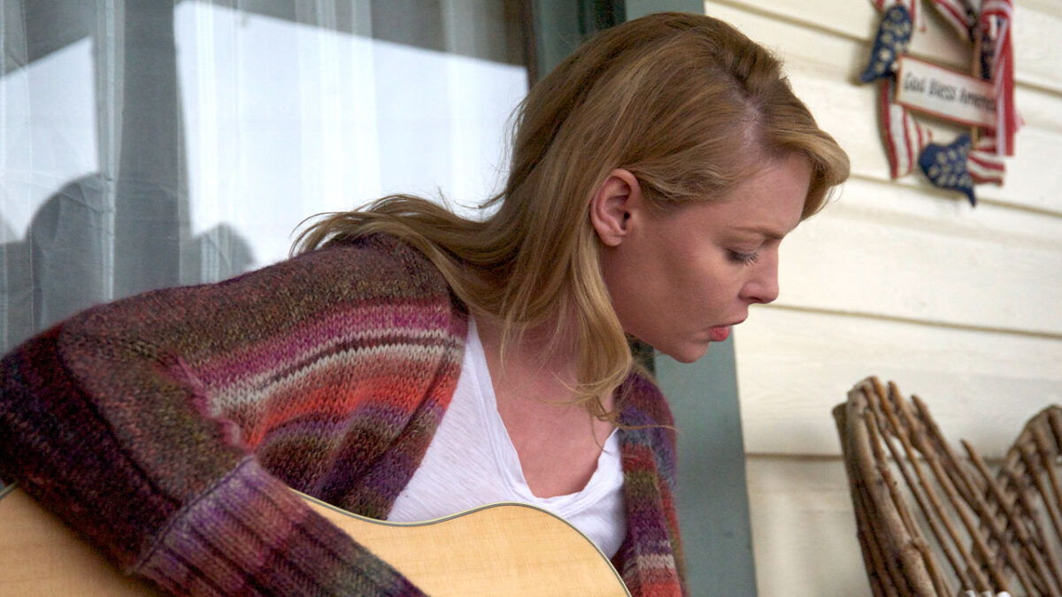 Katherine Heigl toca violão em cena do filme Jackie & Ryan (2014) sentada na varanda com blusa colorida