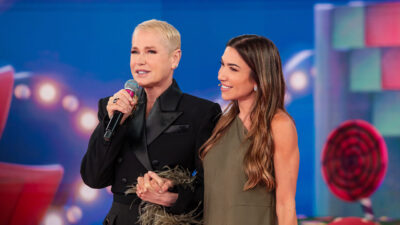 Xuxa Meneghel e Patrícia Abravanel de mãos dadas no palco do Programa Silvio Santos, com Xuxa segurando um microfone
