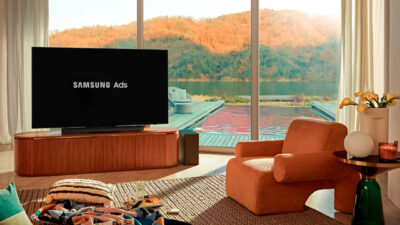 Sala de estar com TV exibindo Samsung Ads voltada para área externa com piscina e paisagem de outono ao fundo
