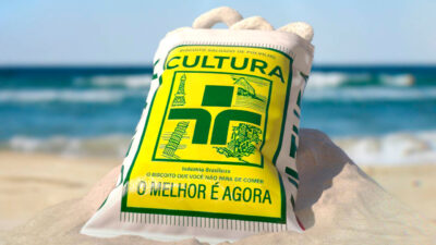 Pacote de biscoito de polvilho Cultura na areia da praia com o mar ao fundo