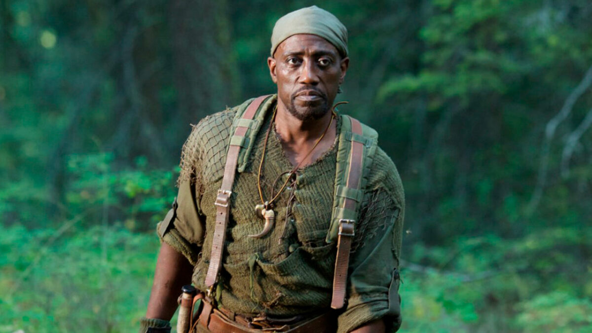 Wesley Snipes caminha por uma floresta usando roupas rústicas e uma bandana na cabeça no filme Invasão Alienígena (2017)