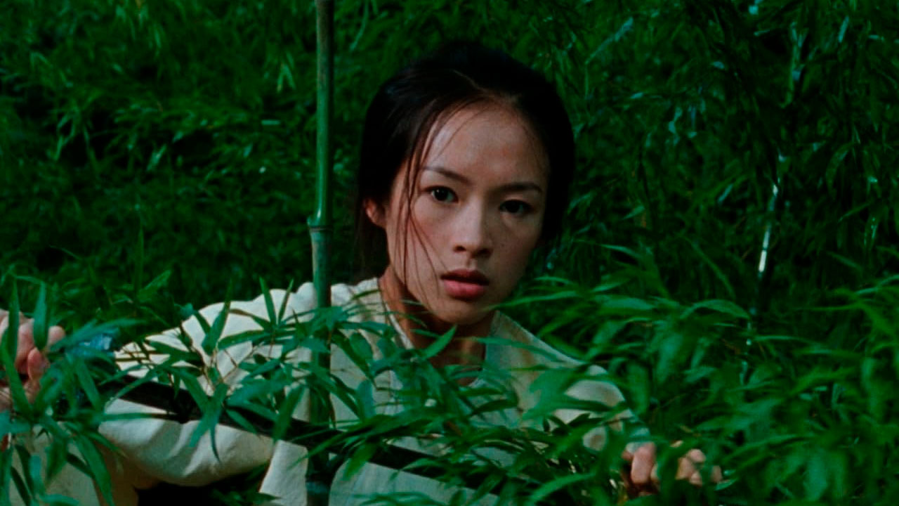 Ziyi Zhang como Jen escondida entre folhas de bambu em cena do filme O Tigre e o Dragão