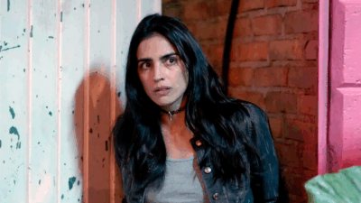 Bárbara de Regil caracterizada como Rosario Tijeras encostada em parede olhando assustada para frente