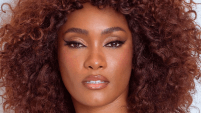 Erika Januza com maquiagem marcada e cabelo cacheado solto em close de rosto para ensaio fotográfico