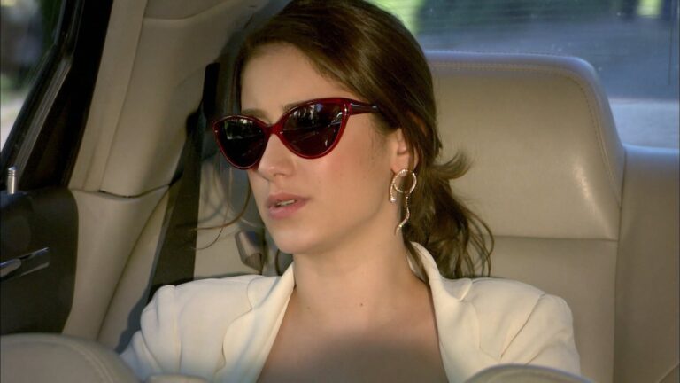 Hazal Kaya caracterizada como Feriha usa óculos escuros e brinco dourado em cena da novela O Segredo de Feriha dentro de um carro