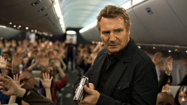 Bill Marks (Liam Neeson) aponta arma em corredor de avião com passageiros de mãos levantadas em Sem Escalas (2014)