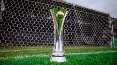 Troféu da Série C do Campeonato Brasileiro posicionado no gramado em frente ao gol com rede hexagonal ao fundo