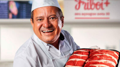 Valdir sorridente com uniforme de açougueiro segurando bandeja com cortes de carne em campanha da Friboi no SBT