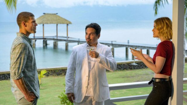 Austin Stowell, Michael Peña e Lucy Hale em cena do filme A Ilha da Fantasia conversando em varanda à beira-mar