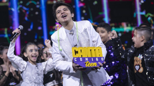 Felipe Sonnesso comemora vitória segurando troféu do Canta Comigo Teen cercado por outros finalistas no palco