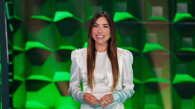 Patricia Abravanel sorrindo durante apresentação do Show do Milhão no SBT com cenário verde ao fundo