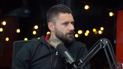 Rafael Sobis fala ao microfone durante participação em podcast com iluminação ao fundo