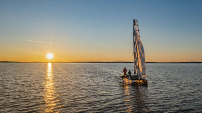Beto Pandiani e Igor Bely em catamarã navegando ao pôr do sol no documentário Rota Polar