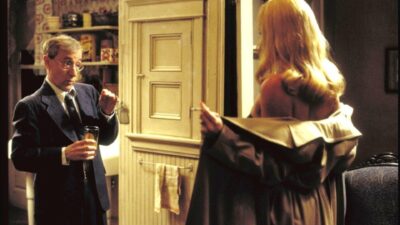 Woody Allen como CW Briggs encara Charlize Theron como Laura Kensington abrindo o sobretudo em O Escorpião de Jade (2001)