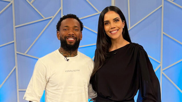 Nego do Borel e Daniela Albuquerque posam sorrindo juntos em estúdio com fundo azul geométrico