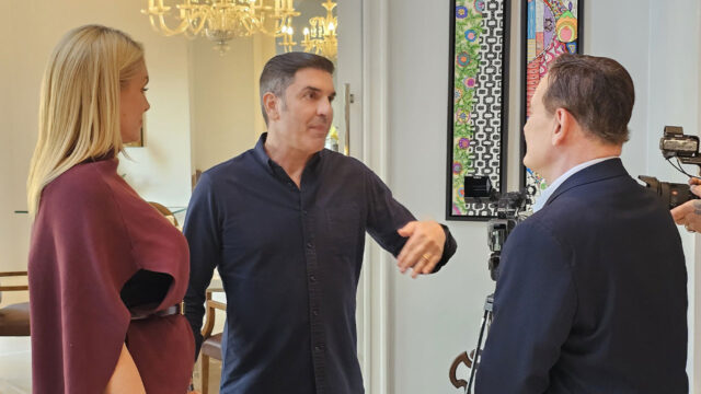 Ana Hickmann, Edu Guedes e Roberto Cabrini conversam em ambiente interno com câmeras ao fundo