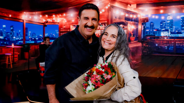Ratinho e Regina Duarte sorrindo juntos com buquê de flores em cenário do Programa do Ratinho