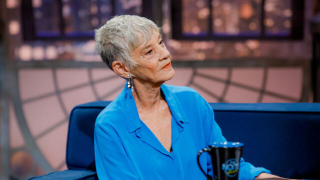 Fátima Souza com blusa azul sentada no sofá do The Noite durante entrevista no SBT